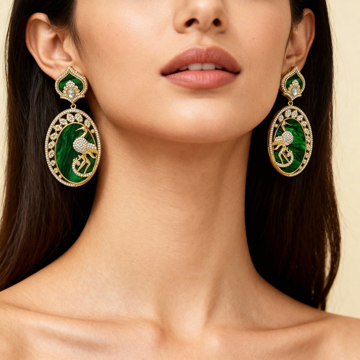 Close-up of a woman wearing green and gold earrings with a neutral background