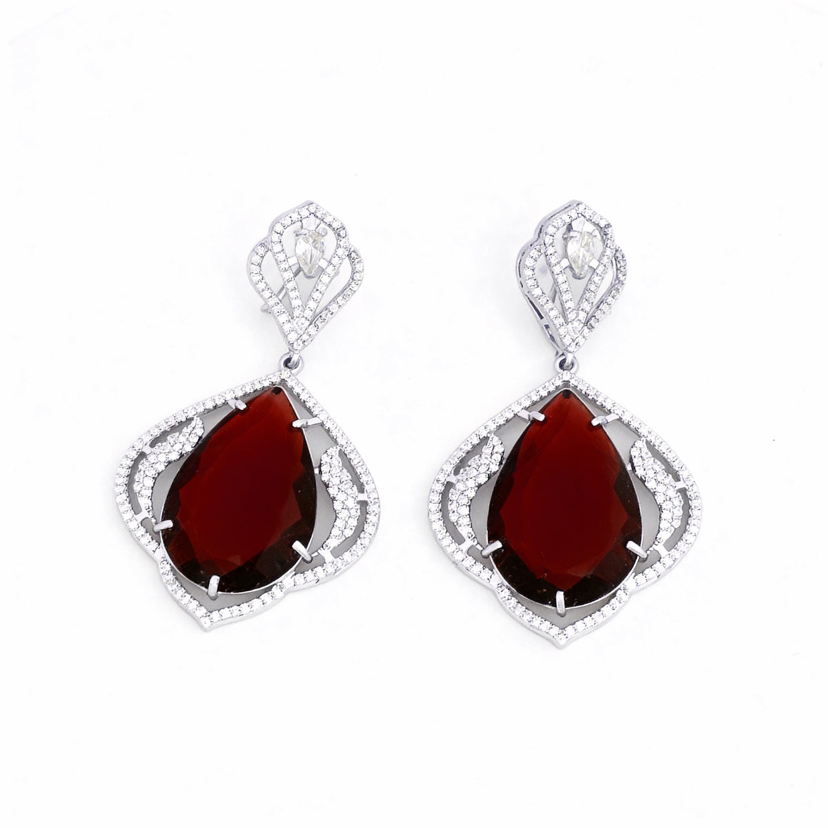 Pair of earrings with red teardrop stones and silver frames on a white background