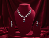 Silver necklace and earrings on a red velvet stand against a red curtain background