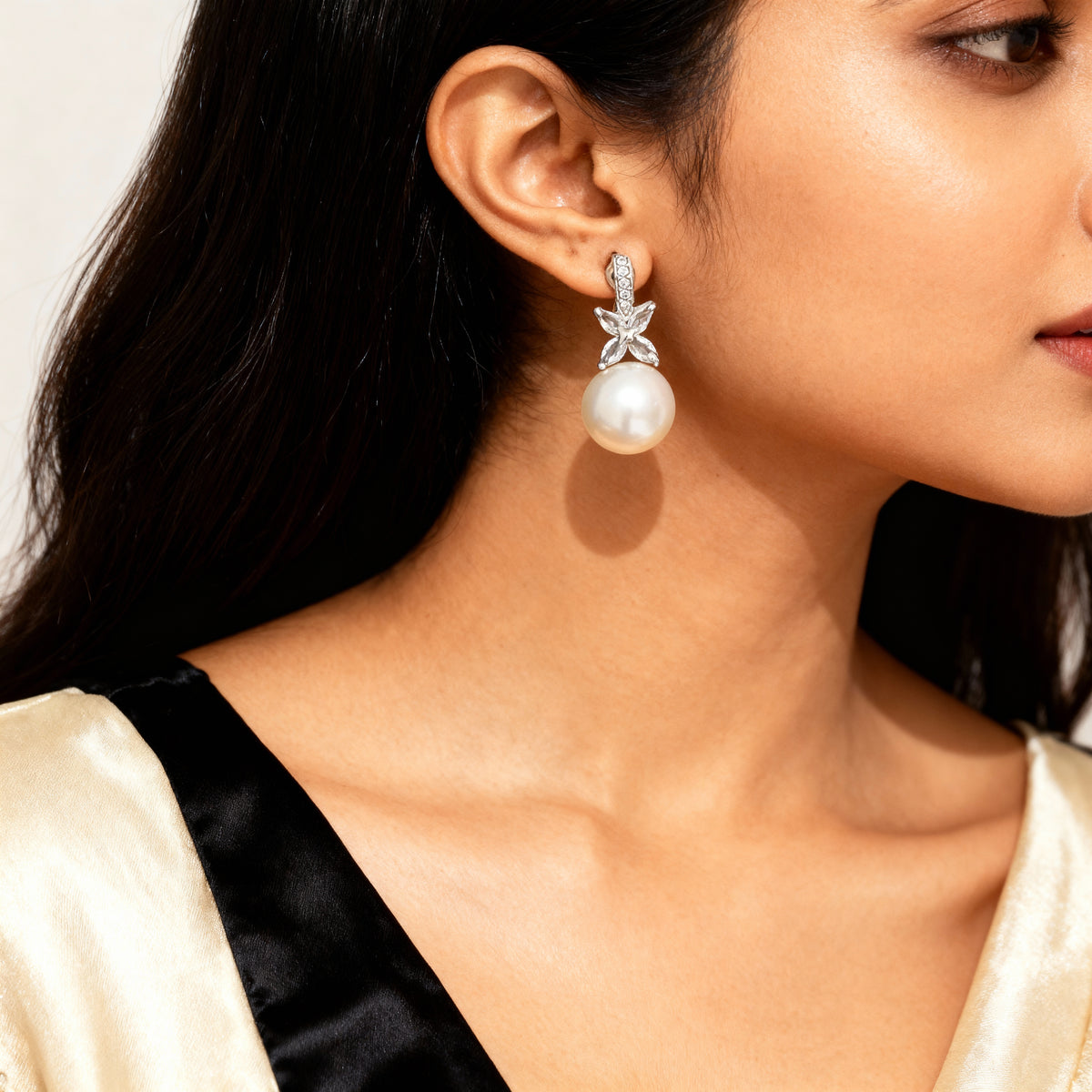 Close-up of a woman wearing a pearl earring with a gold and black outfit.