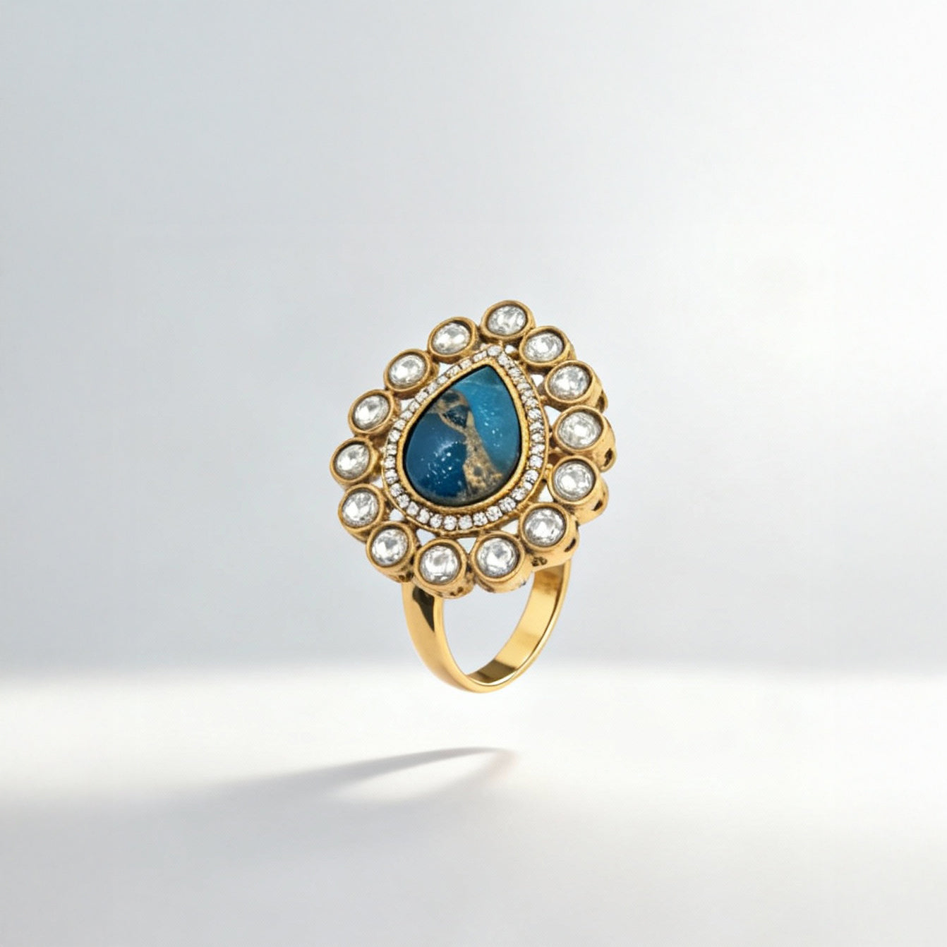 Gold ring with a blue gemstone and pearl accents on a light gray background