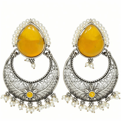 Pair of earrings with yellow teardrop stones and silver floral designs on a white background