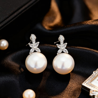 Pearl earrings with silver leaves on a dark fabric background