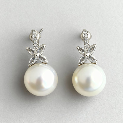 Pearl earrings with silver floral tops on a light gray background