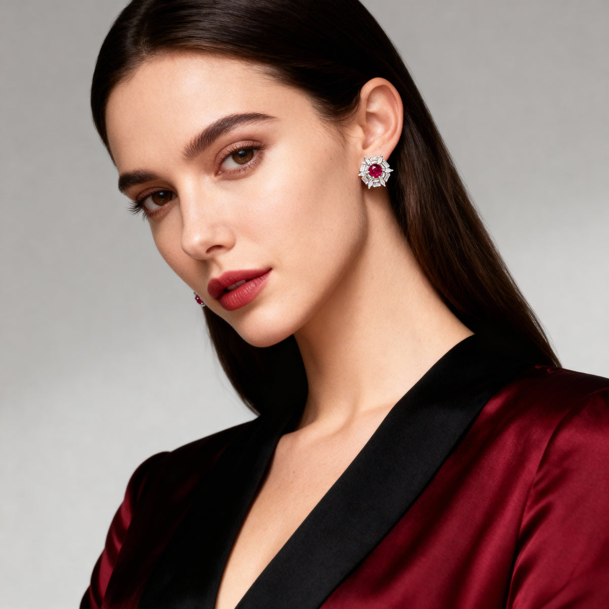 Woman wearing a red satin garment and earrings with a gray background