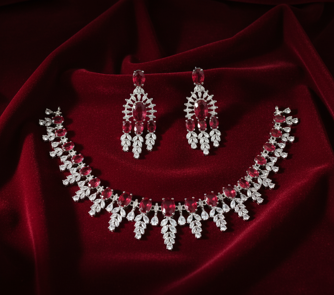 Necklace and earrings set with red and clear stones on a red fabric background