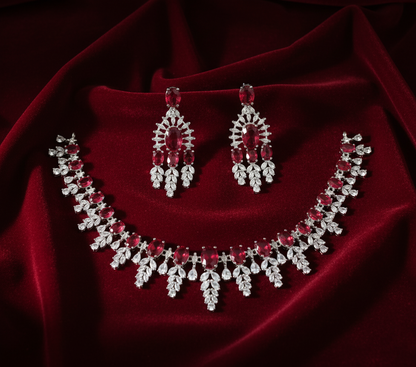Necklace and earrings set with red and clear stones on a red fabric background