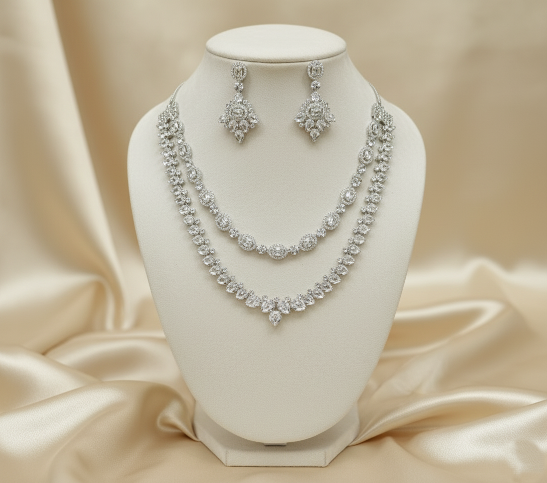 Silver necklace and earrings set on a white mannequin bust with a beige satin background