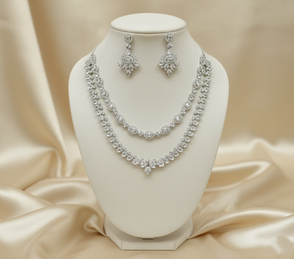 Silver necklace and earrings set on a white mannequin bust with a beige satin background
