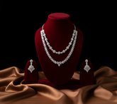 Silver necklace and earrings on a red velvet stand with a brown fabric background
