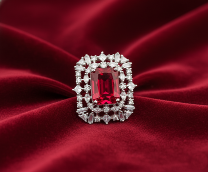 Ring with a red gemstone and diamond accents on a red fabric background